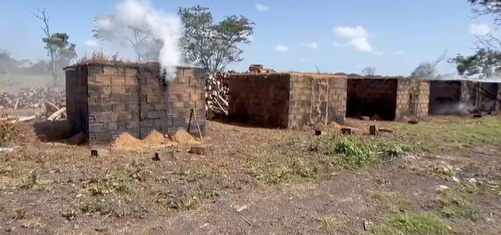 Hornos de ladrillo con leña de eucalipto apilada y humo de la carbonización